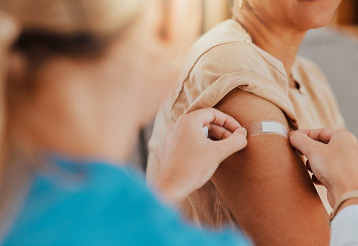 Healthcare, patient and plaster on arm for measles/MMR vaccine, flu shot or arthritis or osteoarthritis injection in hospital for health and wellness. Woman and nurse or doctor together during consultation